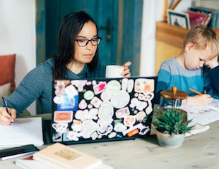 women on laptop working with child beside her