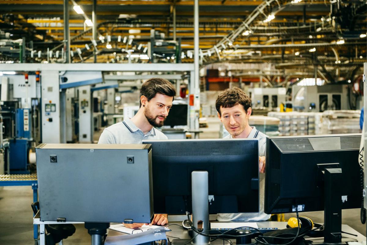 Two technicians at a computer at a factory